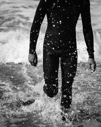 Man in wetsuit splashing water at the beach