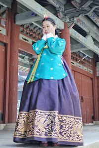 Low angle view of young woman wearing costume standing against built structure