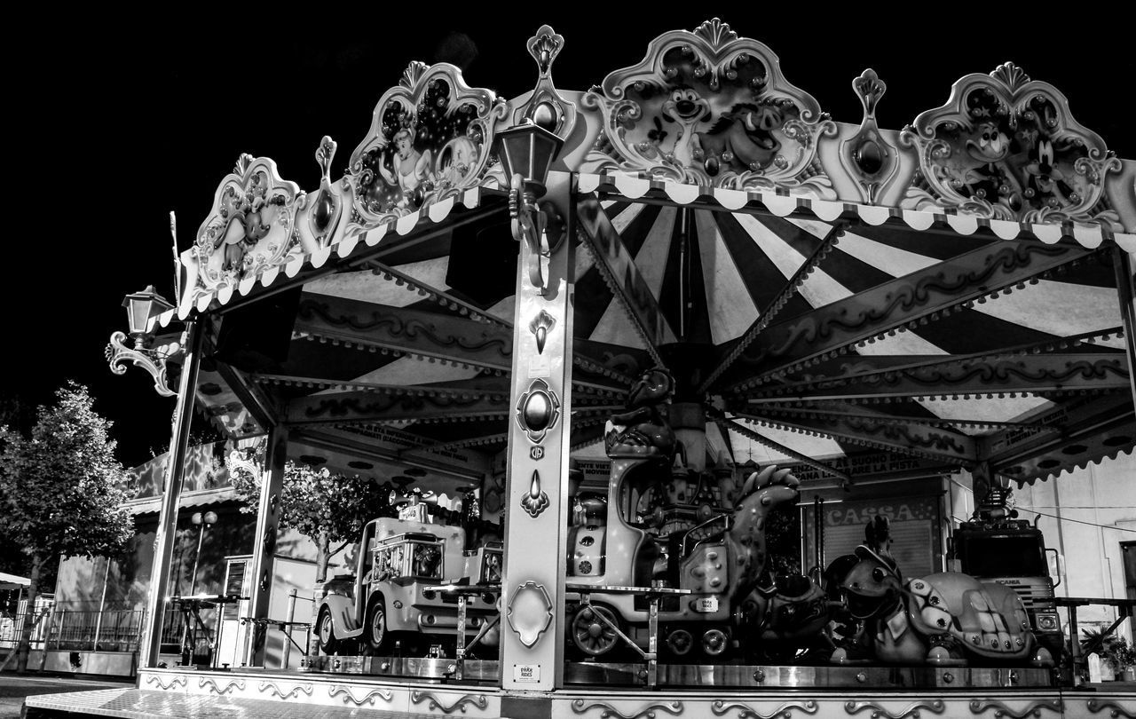 LOW ANGLE VIEW OF CAROUSEL AT AMUSEMENT PARK AGAINST SKY AT NIGHT