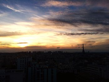 Cityscape against cloudy sky at sunset