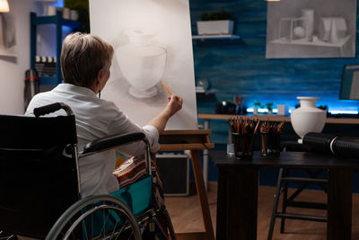 Rear view of woman drawing on canvas at home