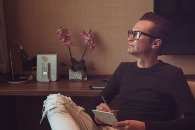 Man looking away while sitting by television set at home