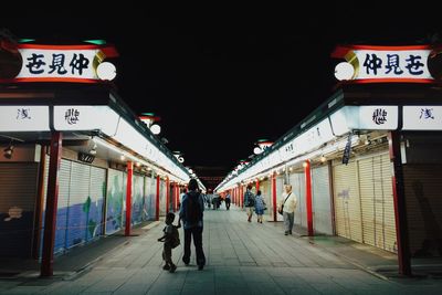 Woman walking on illuminated street at night