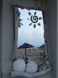 Clothes hanging by window at beach against sky