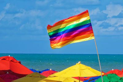 Multi colored flag on beach against sky