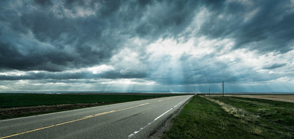 Empty road against cloudy sky