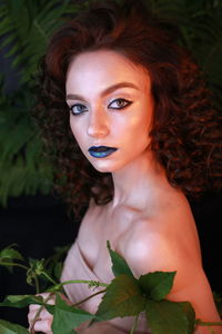 Close-up young woman wearing make-up against plants