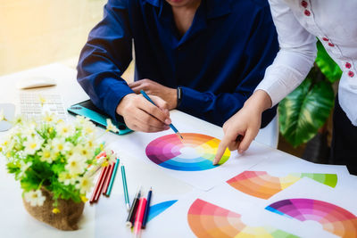 Midsection of man holding multi colored umbrellas on table
