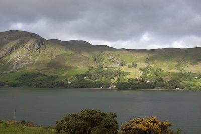 Scenic view of lake and mountains against cloudy sky