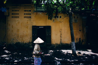 Side view of woman walking against building