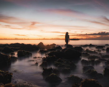 Silhouette man looking at sea against sky during sunset