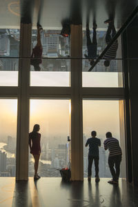 Rear view of silhouette people standing in glass window