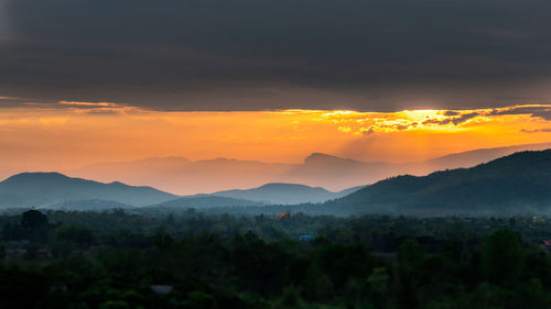 Scenic view of silhouette mountains against orange sky