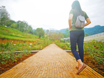 Rear view of backpack woman walking on footpath