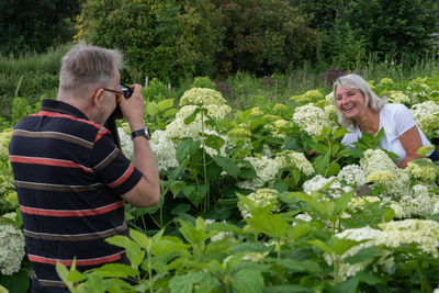 Midsection of woman photographing with umbrella on plants