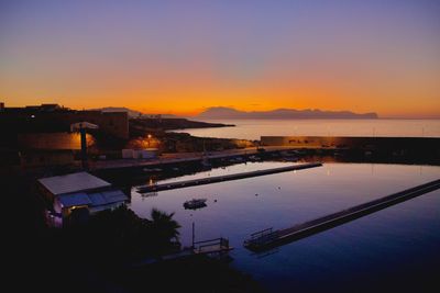 High angle view of swimming pool by building against sky during sunset