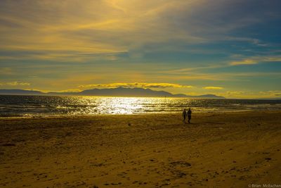 Silhouette man on beach against sky during sunset