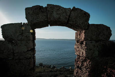 Stone wall by sea against sky