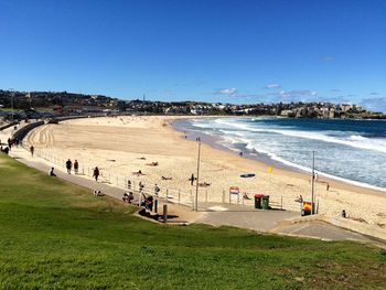 People at beach against clear blue sky