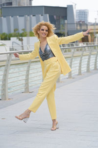 Urban style street fashion photosoot young girl with curly hair wearing yellow trendy suit 