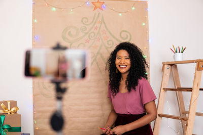 Portrait of smiling woman standing against wall