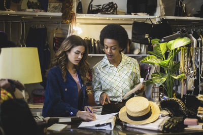 Female owner discussing over document with colleague in boutique