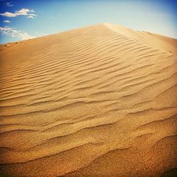 Scenic view of sand dunes against sky