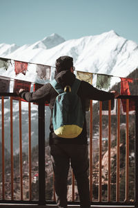 Rear view of man standing against sky and mountains