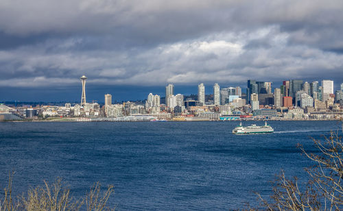 A ferry moves across elliott bay in front of skyscrapers in seattle, washington.