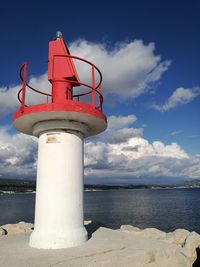 Lighthouse by sea against sky