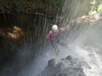 Woman rappelling at waterfall in forest