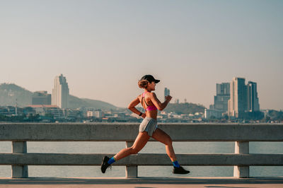 Full length of woman with cityscape against sky