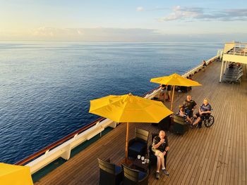 High angle view of people sitting by sea against sky