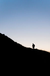 Silhouette man standing on mountain against clear sky