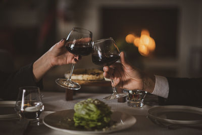 Midsection of man holding wine glass on table