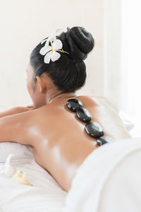 Rear view of woman with stones on back lying at health spa