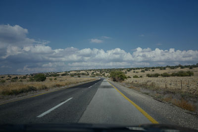 Road by landscape against sky seen through car windshield