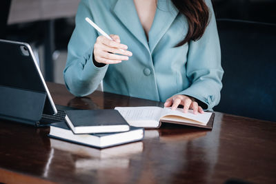 Midsection of businesswoman holding pen