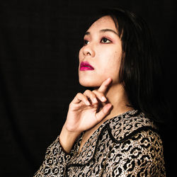 Close-up portrait of a young woman over black background