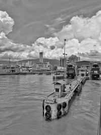 Boats moored at harbor against sky in city