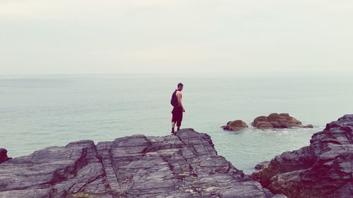 Woman standing on rock formation in sea