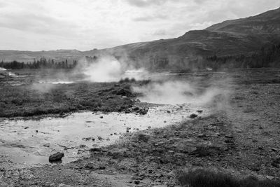 Steam emitting from hot spring against mountain