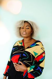 Portrait of woman standing against colored background