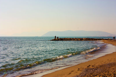 Rocks lined up on the sea water in front of the beach at sunset in versilia and bright colors