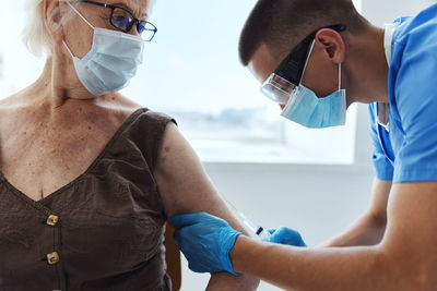 Doctor wearing mask vaccinating woman