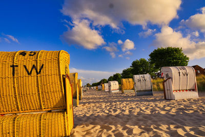 Hooded chairs on beach against sky