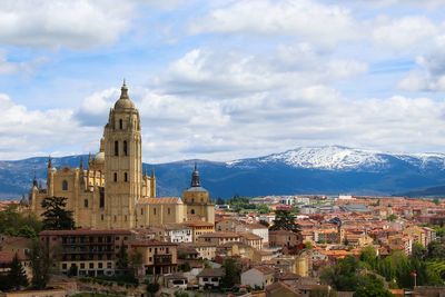 Church and buildings in town against cloudy sky