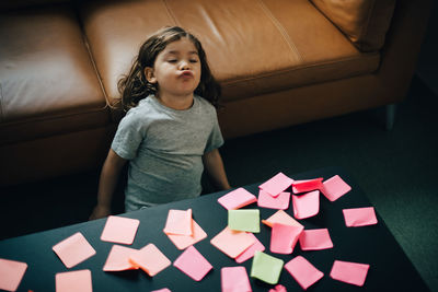 High angle view of tired boy reclining on sofa with adhesive notes on coffee table at office lobby