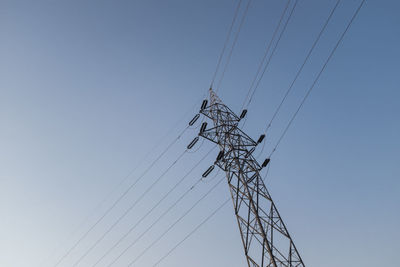 Low angle view of electricity pylon against clear sky