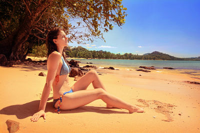 Side view of young woman relaxing on beach